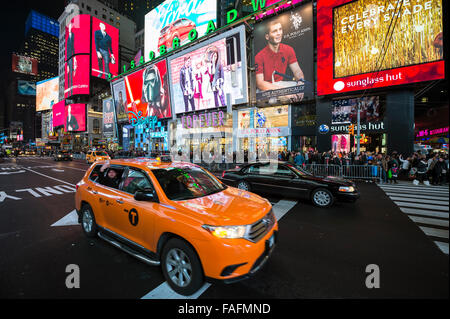 NEW YORK CITY, USA - 22. Dezember 2015: Gelben New Yorker Taxis pass Massen sammeln unter den hellen Lichtern des Times Square. Stockfoto