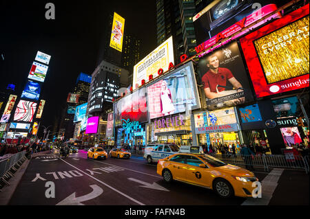 NEW YORK CITY, USA - 22. Dezember 2015: Gelben New Yorker Taxis pass Massen sammeln unter den hellen Lichtern des Times Square. Stockfoto