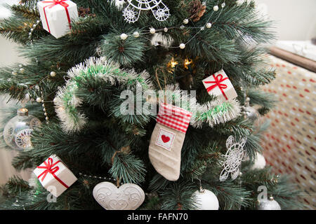 Weihnachten Tannenbaum mit hängenden Dekorationen hautnah mit Strumpf Kugeln, Lametta und präsentiert Stockfoto