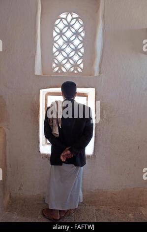 Eine jemenitische Mann schaut aus dem Fenster in den Dar al-Hajar, Dar al Hajar, die Rock-Palast, royal Palace, Wahrzeichen des Jemen Stockfoto