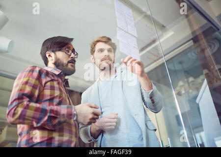 Junge Mitarbeiter diskutieren Hinweise auf Briefpapiere in Büro Stockfoto