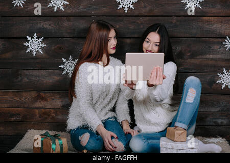 Zwei schöne Mädchen mit einem Tablet, zwischen Geschenke Stockfoto