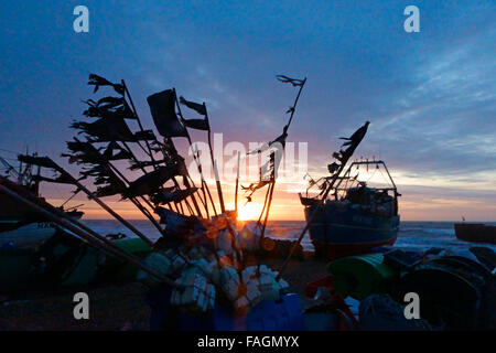 Hastings, East Sussex, UK. 30. Dezember 2015. Winter Sonnenaufgang über die Fischerboote an der Hastings Stade Strand. Stockfoto