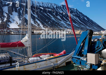 Eine Yacht auf der Werft in Isafjördur gegen den dramatischen Hügeln und Bergen im Hintergrund, in den Westfjorden Nordisland Stockfoto