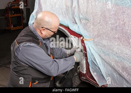 Karosserie Firma arbeitet auf einem Flügel mit einem Winkelschleifer. Stockfoto