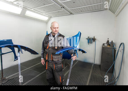Fahrzeug-Lackierer prüft die lackierten Fahrzeugteile. Stockfoto