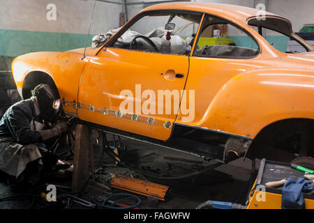 Karosseriebauer stellt ein Oldtimer VW Karmann Ghia. Schweißarbeiten in der Rad-Gehäuse. Stockfoto