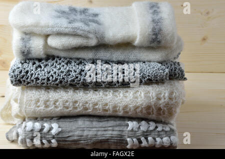 Haufen von grauen und weißen weichen wollenen Pullover und Schal mit ein paar Handschuhe auf der Oberseite Stockfoto