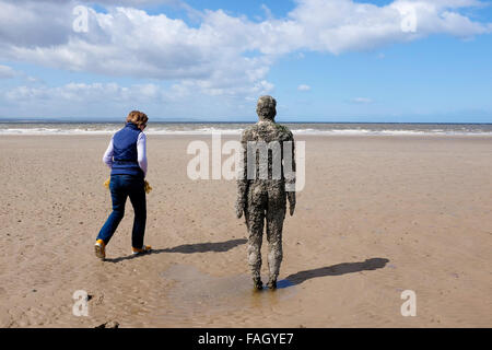 Eine Frau steht neben einem die eisernen Männer, Antony Gormley woanders Kunstinstallation am Crosby Strand Stockfoto