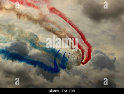 RAF rote Pfeile Anzeige Kunstflugstaffel malen Gewitterhimmel mit rot, weiß und blau Rauch. Stockfoto