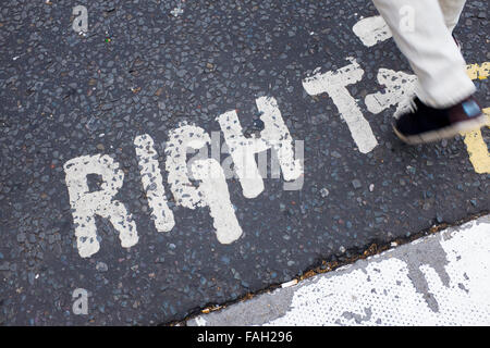 Fuß auf einer Straße in London mit einem Blick rechts Schild gemalt auf dem Asphalt unter den Füßen, Fußgänger zu übermitteln. Stockfoto