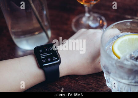 Junge Frau mit einer Apple Watch in einer Bar trinken Stockfoto