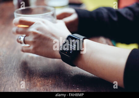 Junge Frau mit einer Apple Watch in einer Bar trinken Stockfoto