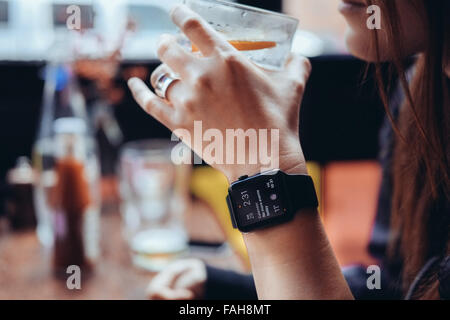 Junge Frau mit einer Apple Watch in einer Bar trinken Stockfoto