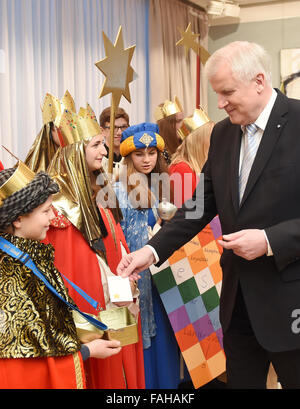 Horst Seehofer (R), Premier des deutschen Staates Bayern, legt einen Umschlag in eine Spendenbox des star Sänger in der Staatskanzlei in München, 30. Dezember 2015. Seehofer erhalten vier Gruppen von star Sänger aus dem Bistum Würzburg. Foto: TOBIAS HASE/dpa Stockfoto