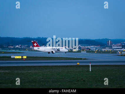 Eine Avro RJ100 Passagierjet der Swiss International Airlines ist in der Abenddämmerung am internationalen Flughafen Zürich Rollen. Stockfoto