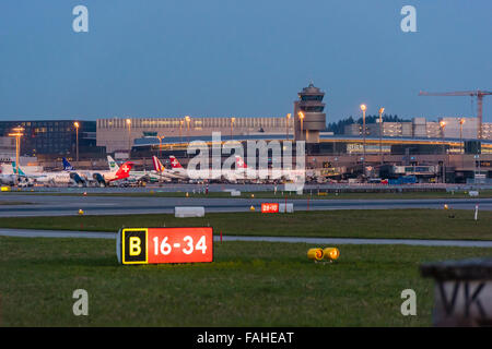 Beleuchtete Piste Signalisations- und belebten Boden Verkehr in der Abenddämmerung am internationalen Flughafen Zürich. Stockfoto