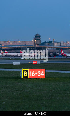 Beleuchtete Piste Signalisations- und belebten Boden Verkehr in der Abenddämmerung am internationalen Flughafen Zürich. Stockfoto