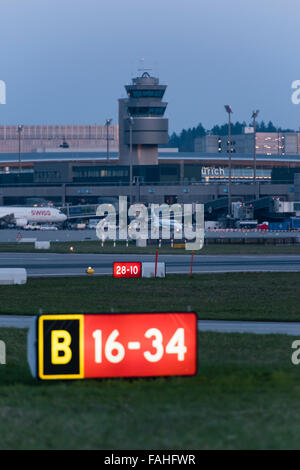 Beleuchtete Piste Signalisations- und belebten Boden Verkehr in der Abenddämmerung am internationalen Flughafen Zürich. Stockfoto