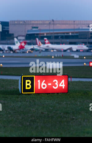 Beleuchtete Piste Signalisations- und belebten Boden Verkehr in der Abenddämmerung am internationalen Flughafen Zürich. Stockfoto