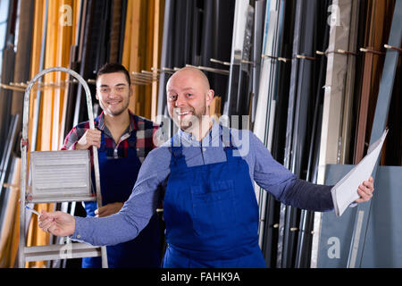 Sorgfältige Arbeiter in Overall Betrieb in Drehbank, seinen Chef mit Papieren in der Nähe Stockfoto