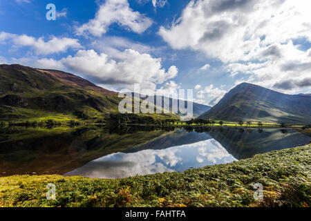 Lake Buttermere reflektieren die umliegenden Hügel an einem hellen sonnigen frühen Herbsttag Stockfoto