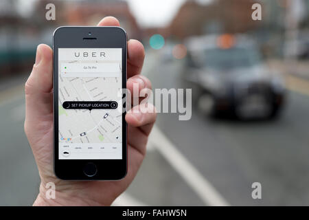 Ein Mann nutzt die Uber-Taxi-Smartphone-app während Stand an einem Taxistand (nur zur redaktionellen Verwendung) Stockfoto