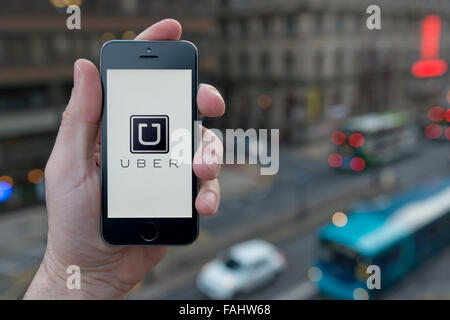 Ein Mann nutzt die Uber-Taxi-Smartphone-app während Stand in einem hohen Gebäude mit Blick auf einer belebten Straße (nur zur redaktionellen Verwendung) Stockfoto