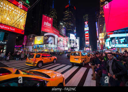 NEW YORK CITY, USA - 22. Dezember 2015: Gelben New Yorker Taxis pass Massen sammeln unter den hellen Lichtern des Times Square. Stockfoto