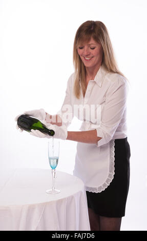 Kellnerin mit weißen Handschuhen, gießen ein Glas Champagner Stockfoto