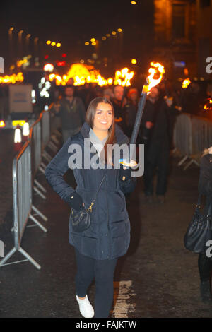 Edinburgh, Schottland. 30. Dezember 2015. Ein hübsches Mädchen marschiert mit einer flammenden Fackel zu Beginn der Hogmanay Feiern. Hinter ihr zusammenführen Tausende von anderen Fackeln in einen goldenen Weg auf König George IV Bridge. Brian Wilson/Alamy Live-Nachrichten. Stockfoto