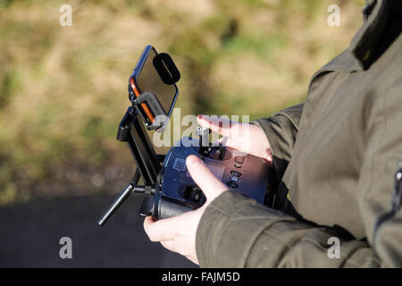 Mann außerhalb Steuerung Drohne von Handy oder Tablet-Bildschirm mit Daumen auf Fernbedienung Sticks. Stockfoto