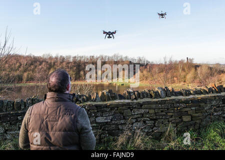 Mann außerhalb Steuerung Drohne von Handy oder Tablet-Bildschirm. Zwei Drohnen im Blick fliegen. Stockfoto