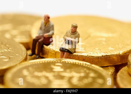 Miniatur-Leute sitzen auf Schokolade Geld Münzen Stockfoto