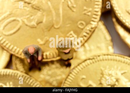 Miniatur-Leute sitzen auf Schokolade Geld Münzen Stockfoto