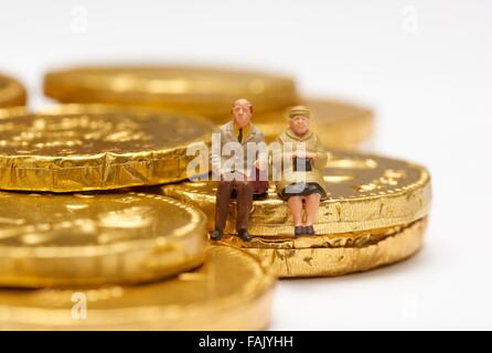 Miniatur-Leute sitzen auf Schokolade Geld Münzen Stockfoto