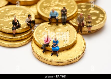 Miniatur-Leute sitzen auf Schokolade Geld Münzen Stockfoto