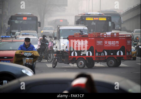 Zwei elektrische Dreiräder für Tmall.com pendeln zwischen starkem Verkehr in Peking, China. Stockfoto