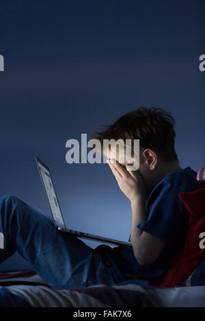 Online-Mobbing, Cyber-Mobbing Foto eines verärgert jungen in seinem Schlafzimmer Blick auf Nachrichten auf social media Stockfoto