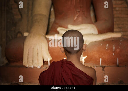 Rückansicht der junge Novize mit Kerzenlicht in einem buddhistischen Tempel, Bagan, Myanmar zu beten. Stockfoto