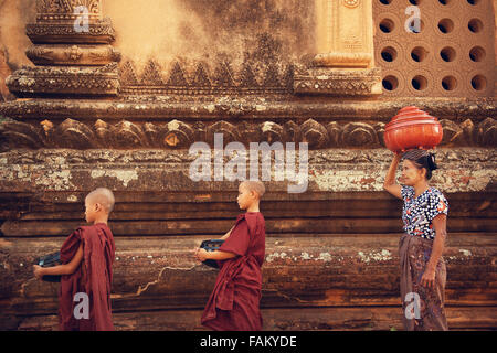 Buddhistischen Novizen gehen um Almosen und Angebote im alten Bagan, Myanmar zu sammeln. Die Prozession findet jeden Morgen statt. Stockfoto