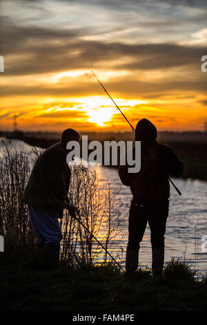 Zwei Angler Angeln in der Sonne steigt über den Fens in bei Burwell Lode bei Wicken Fen, Cambridgeshire. Stockfoto