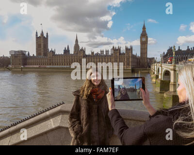 Touristen mit einem iPad, um sich vor den Houses of Parliament in London, UK zu fotografieren. Stockfoto