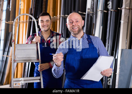 Glückliche Arbeiter in Overall Betrieb in Drehbank, seinen Chef mit Papieren in der Nähe Stockfoto