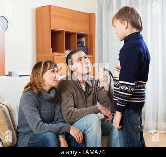 Mutter und Vater mit Gürtel beschimpfen Teenager-Jungen zu Hause. Eltern im Fokus Stockfoto