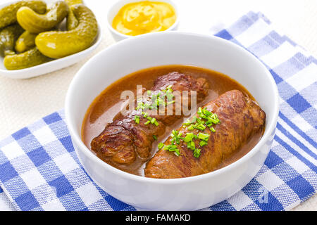 Zwei Rouladen Rind in Schüssel mit Soße, Senf und Gurken Stockfoto