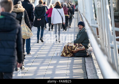 Menschen zu Fuß vorbei an einem Obdachlosen auf Hungerford Bridge in London betteln. Stockfoto