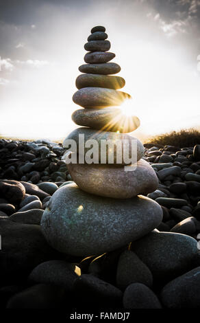 Die Morgensonne scheint durch einen Stapel von Kiesel am Strand. Stockfoto