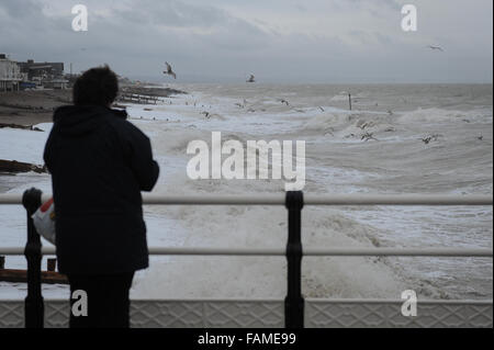 Eine Frau steht auf Worthing Pier und nimmt ein Foto der großen Wellen auf den Strand am Neujahrstag in Worthing, West Sussex, England. Stockfoto