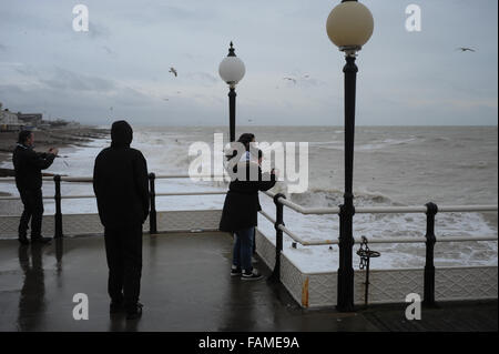 Menschen stehen auf Worthing Pier und beobachten die großen Wellen auf den Strand am Neujahrstag in Worthing, West Sussex, England. Stockfoto